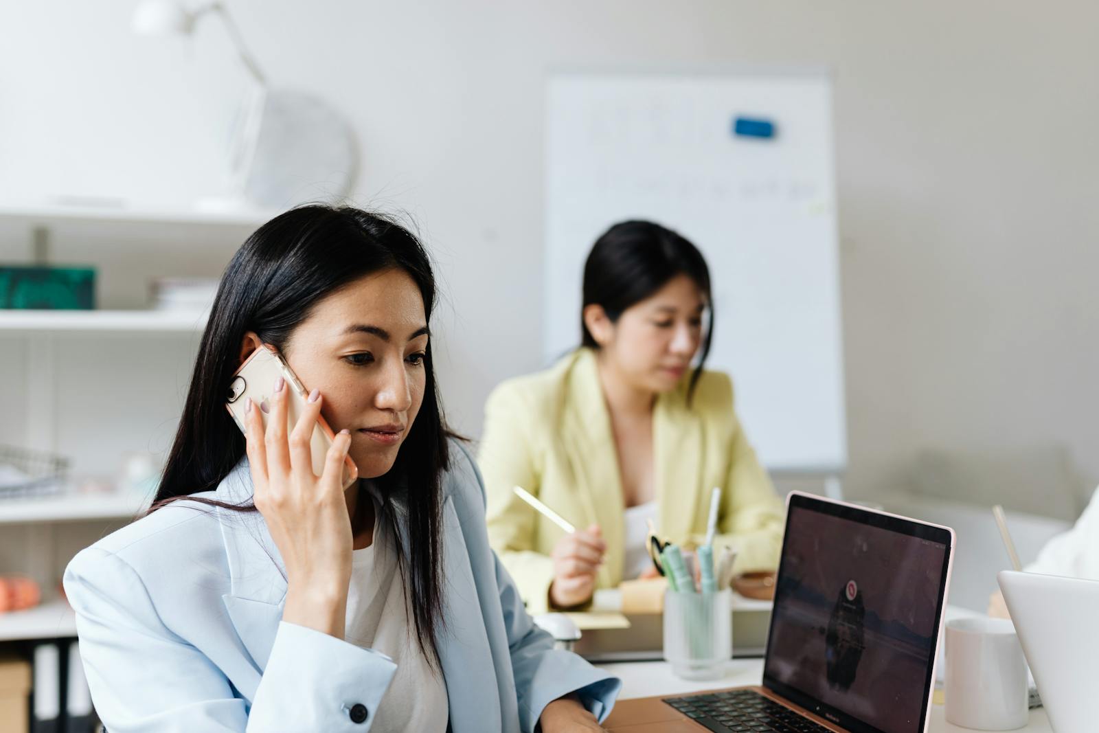 Business owner balancing a laptop session and a phone call while coordinating the day's work.
