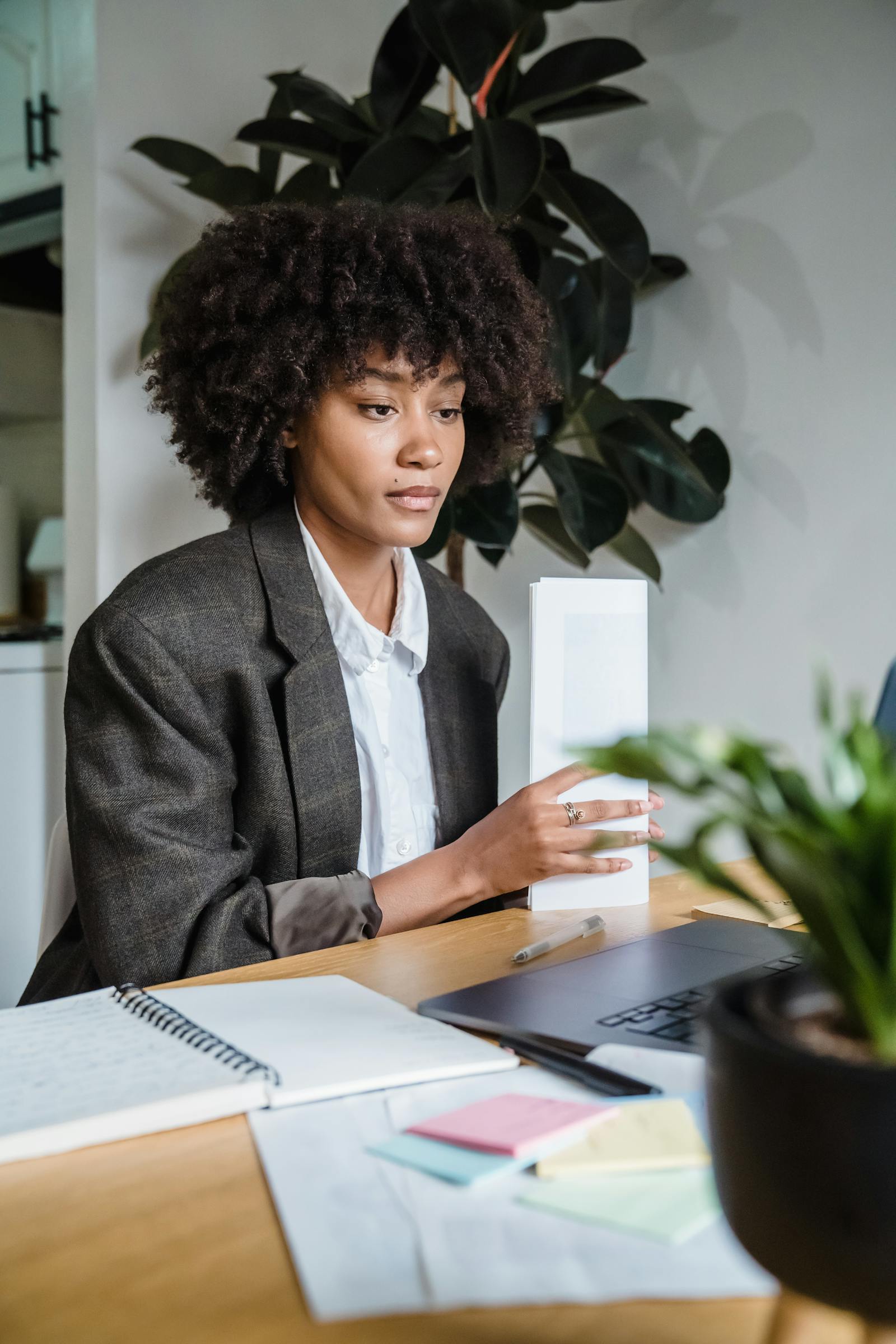 Independent consultant working from a bright home office with a laptop and notes spread across the desk.
